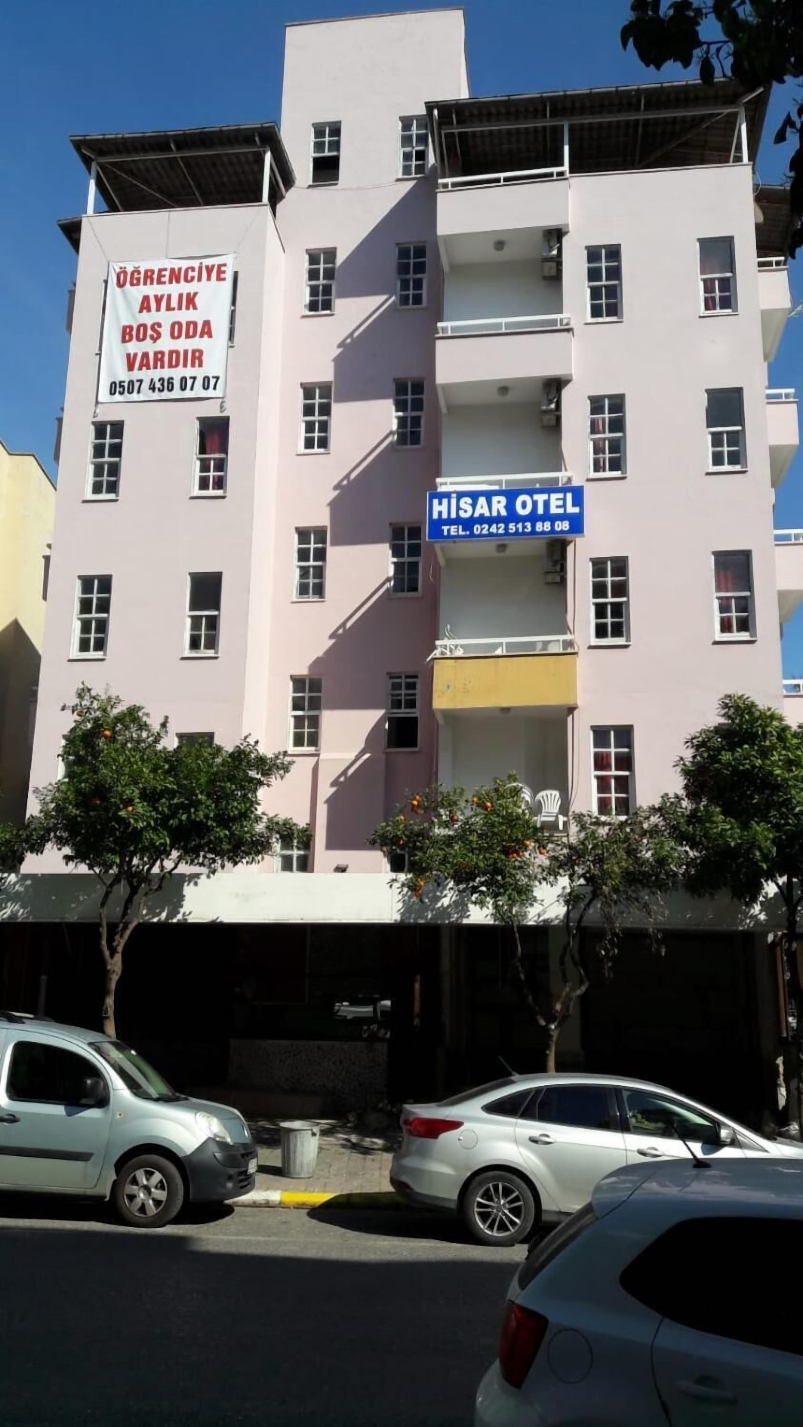 Un edificio de varios pisos con un letrero que dice 'HISAR OTEL' y otro letrero que indica 'Hay habitaciones vacías mensuales para estudiantes'.