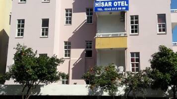 Un edificio de varios pisos con un letrero que dice 'HISAR OTEL' y otro letrero que indica 'Hay habitaciones vacías mensuales para estudiantes'.