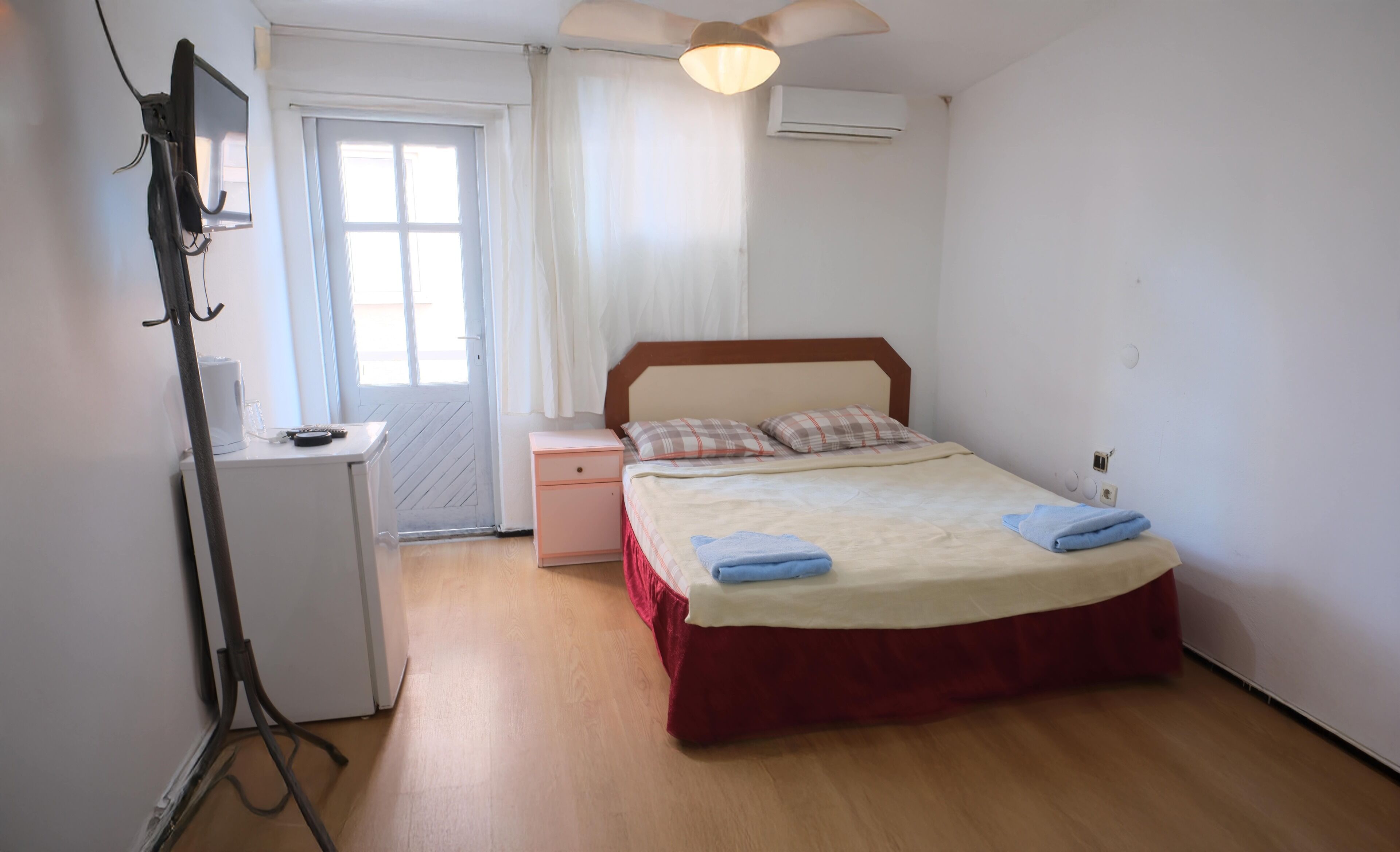 A bedroom with a bed, a desk, a chair, a wardrobe, and a ceiling fan.