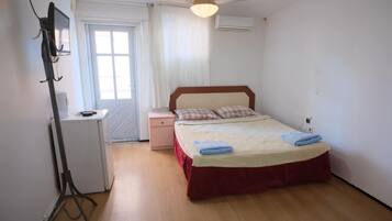 A bedroom with a bed, a desk, a chair, a wardrobe, and a ceiling fan.