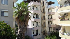 A multi-story residential building with balconies, a central stairwell, and surrounding greenery. - Hisar Otel (Alanya)