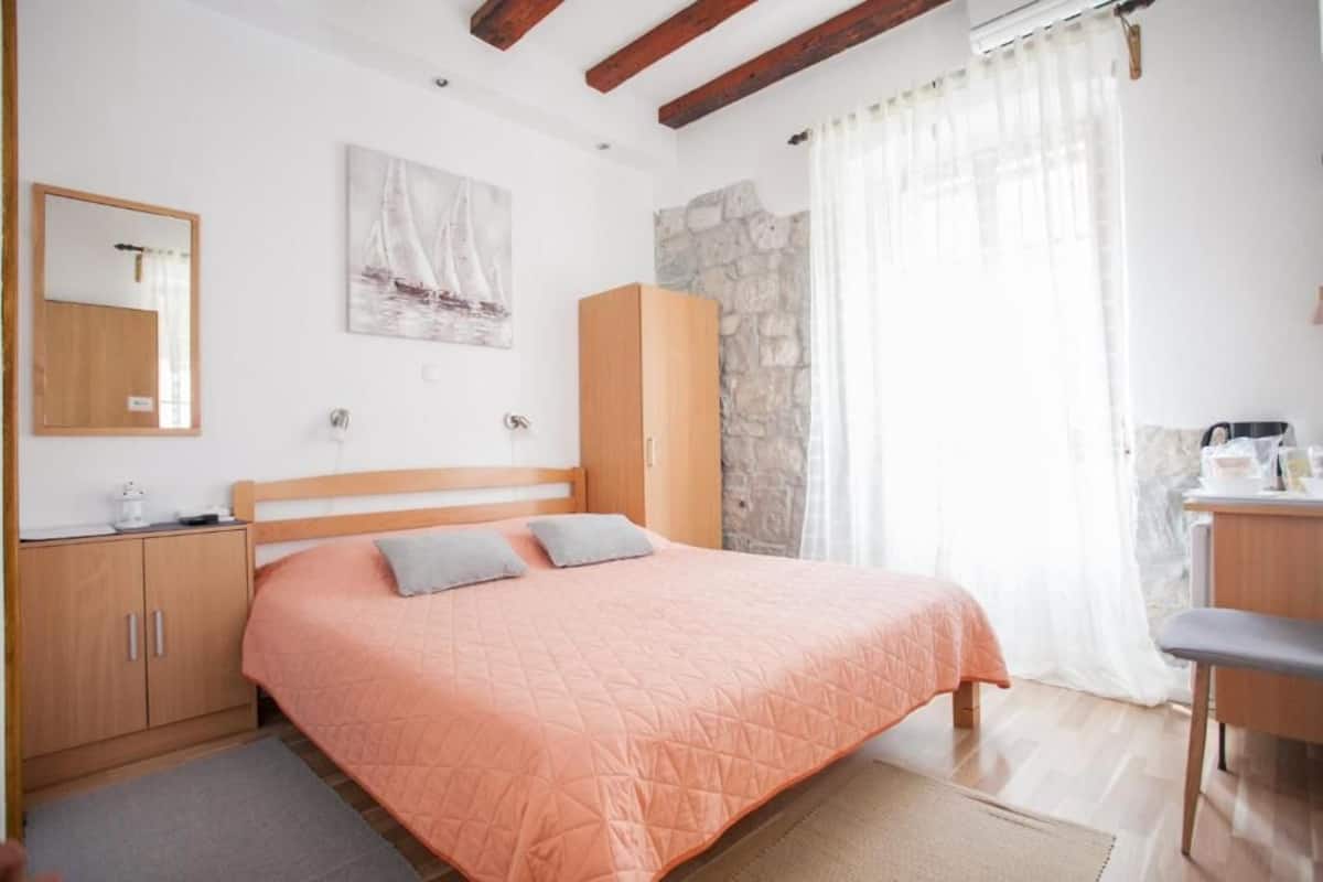 Un dormitorio con cama, armario, escritorio, espejo y un cuadro en la pared.