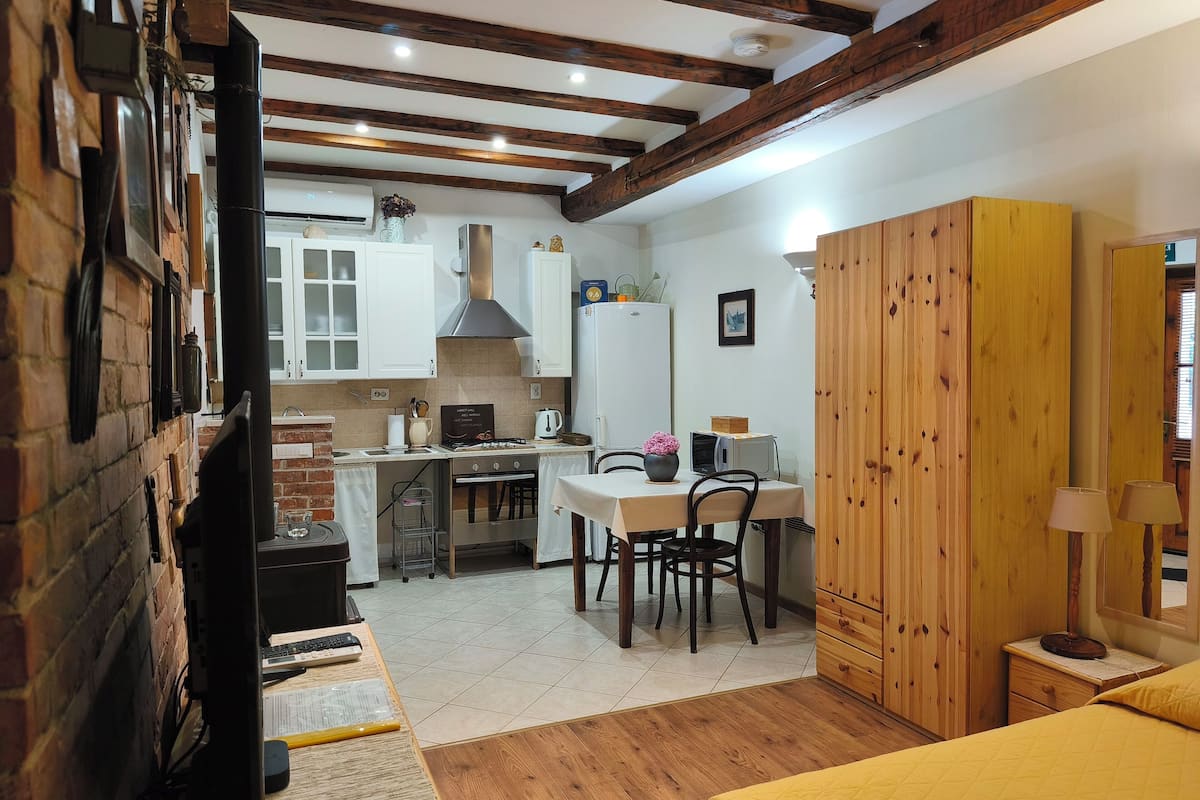 Una cocina compacta con armarios blancos, una estufa y un comedor con mesa y sillas.