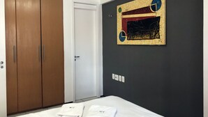 A hotel room with a bed, a wardrobe, a door, and a wall-mounted artwork. - Altavista Apartments (Fortaleza)
