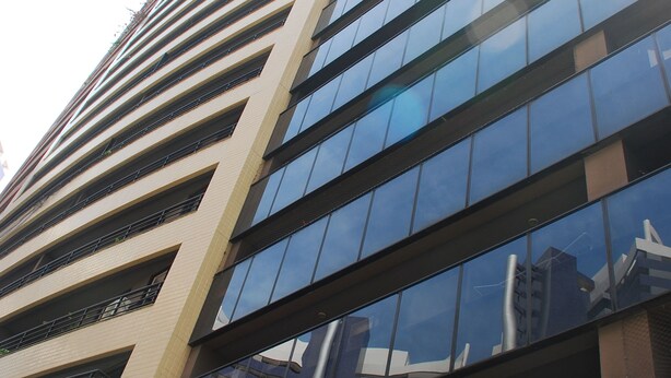 A tall, modern building with a reflective glass facade and multiple balconies. - Altavista Apartments (Fortaleza)