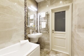 A modern bathroom with a bathtub, sink, and a door.