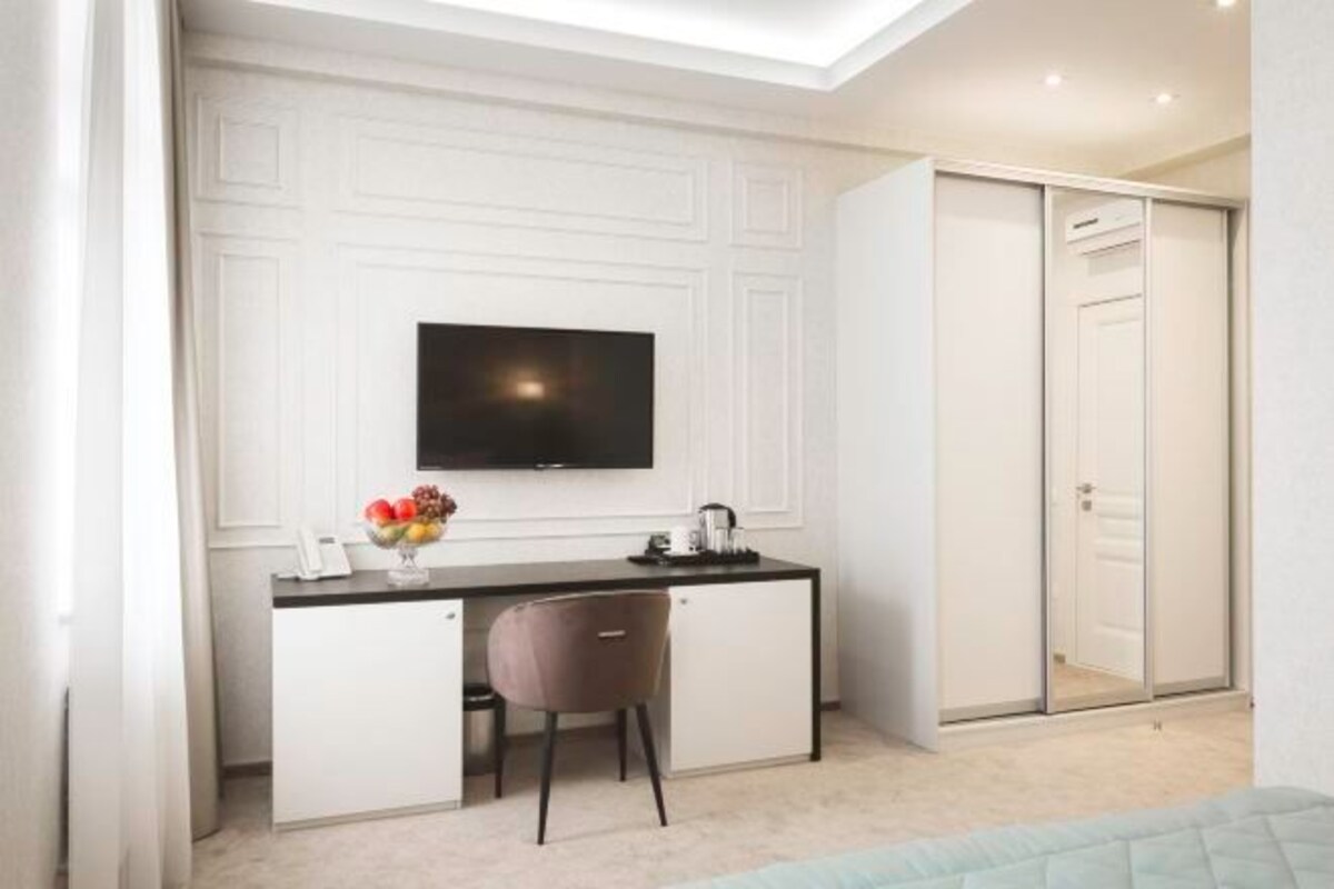 A modern bedroom with a bed, a desk with a chair, a television, and a wardrobe.