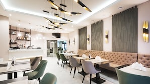 Un restaurante moderno con barra, varias mesas para comer y una zona de estar con un banco acolchado.
