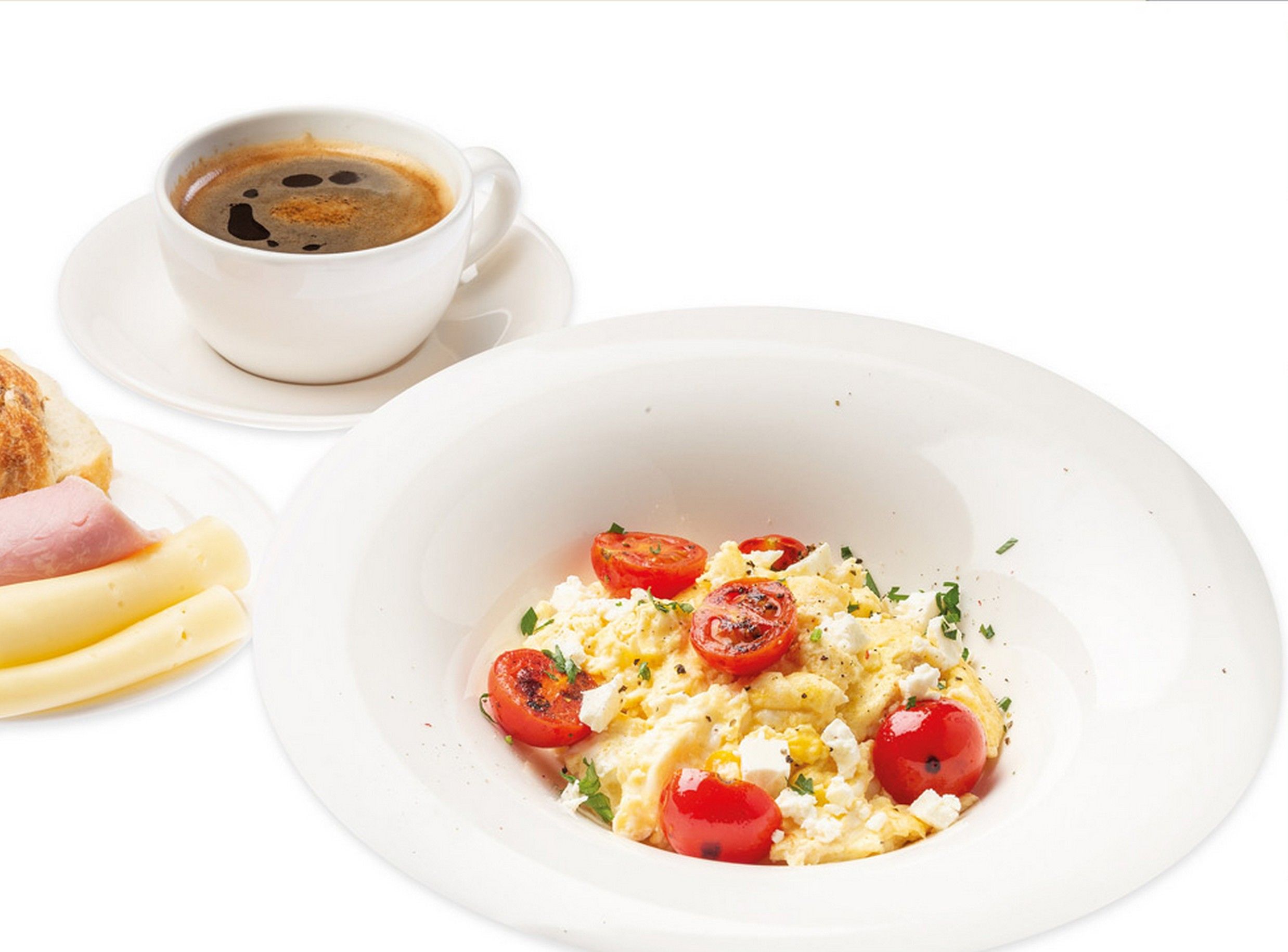 A breakfast setting with scrambled eggs, tomatoes, and cheese on a plate, a cup of coffee, and a side of toast and ham.