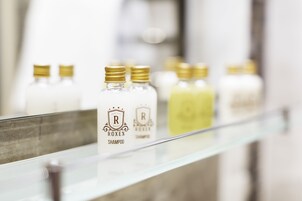 Una fila de botellas con tapones dorados sobre una estantería de vidrio.