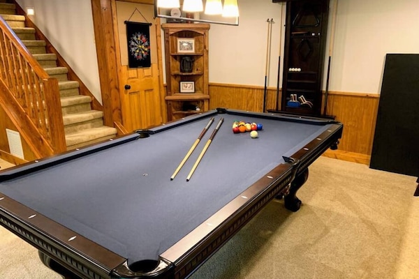 A spacious game room with a pool table, dartboard, and warm lighting creates the perfect setting for family fun and group entertainment during your stay.