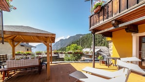 Una terraza de madera con una mesa y sillas, con vistas a un paisaje montañoso.