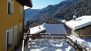 Un edificio amarillo con balcón que da a un paisaje montañoso nevado.