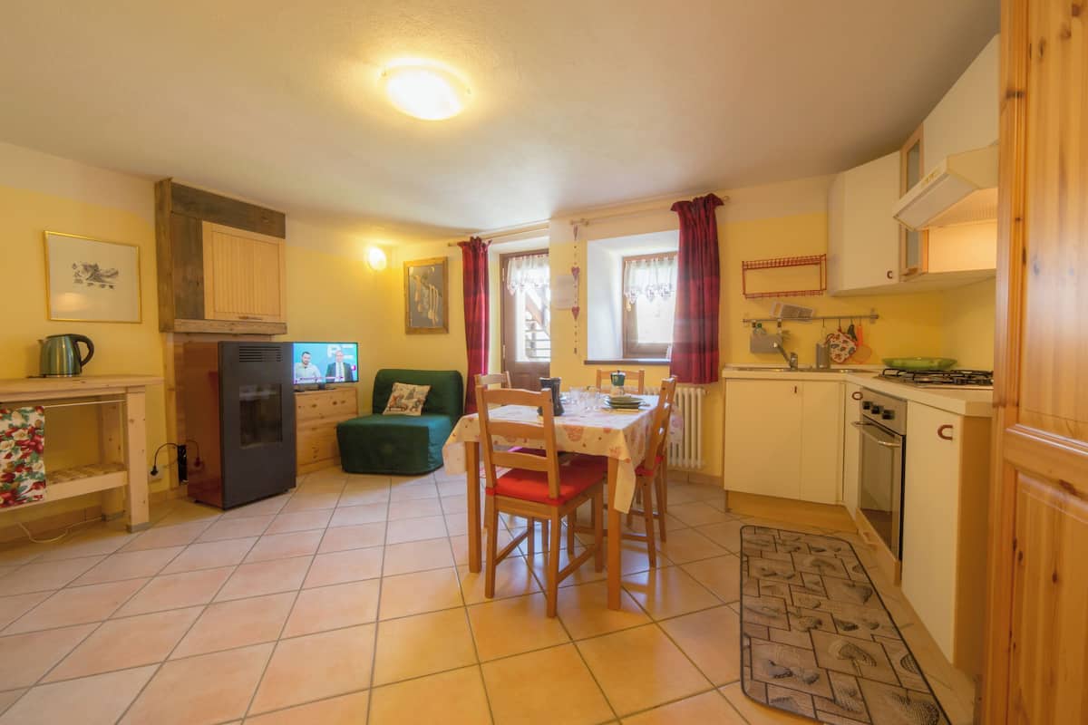 A compact kitchen with a dining table, chairs, a refrigerator, and a stove.