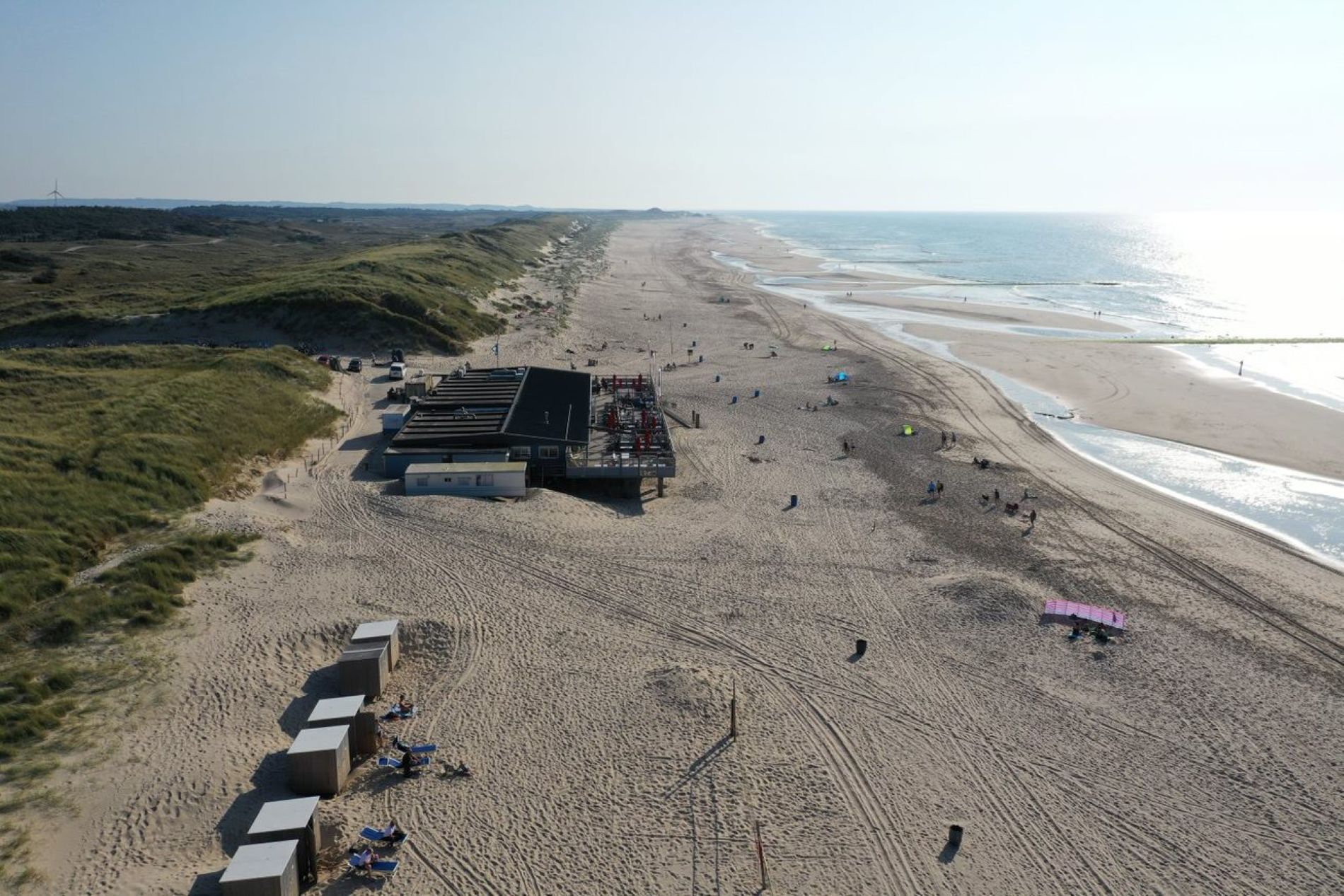 A beach with a row of beach huts and a lifeguard tower.