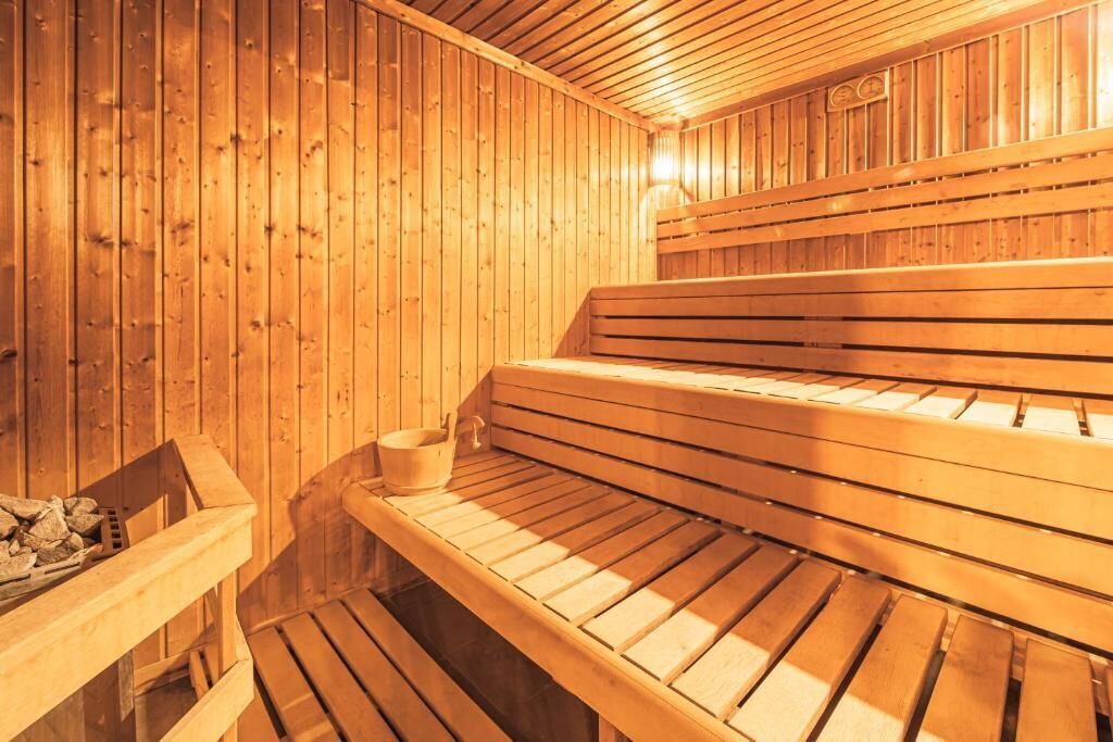 A sauna with wooden benches and a bench with a bucket.