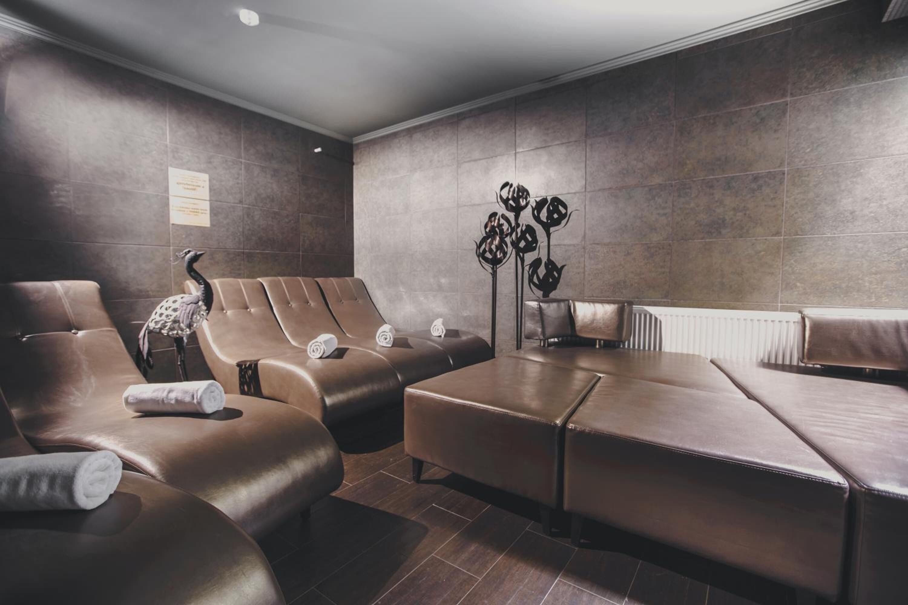 A spa area with leather seating, a decorative wall piece, and a small table with towels.