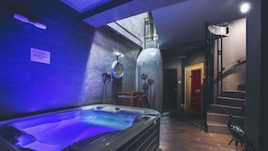 A modern spa area with a hot tub, a clock, and a staircase.