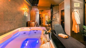 A spa room with a hot tub, a bottle of champagne, and two glasses of wine.