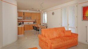A compact living space with a kitchen, dining area, and a sofa. - Il Cedro (Salò)