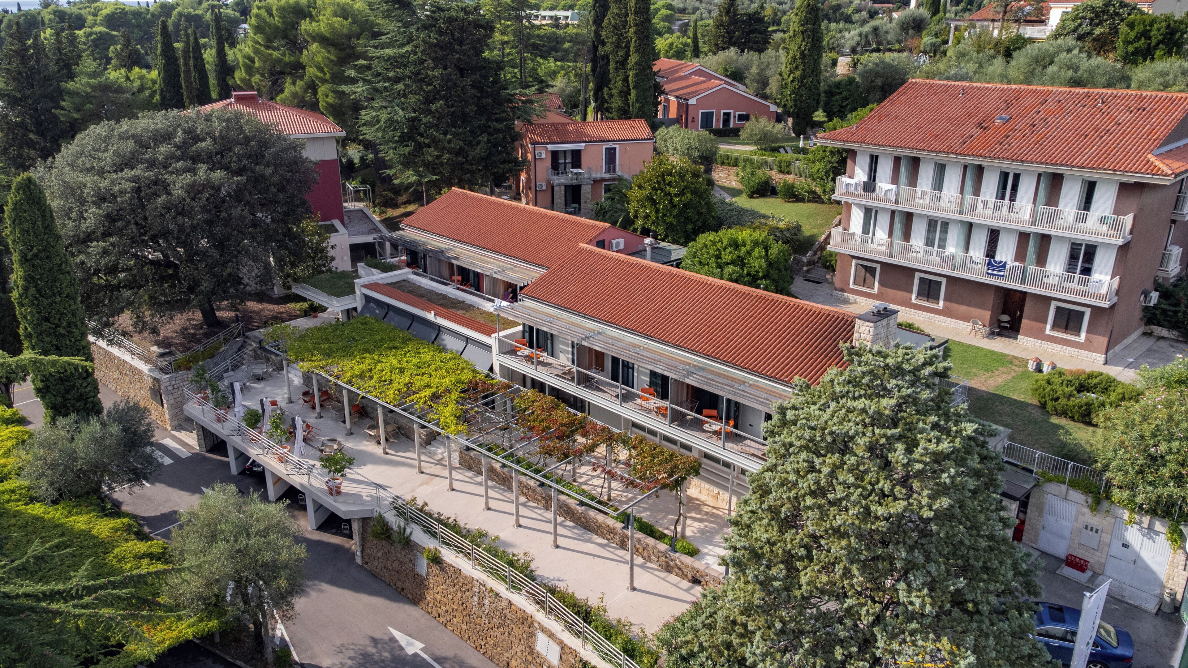 A multi-story building with a red-tiled roof, balconies, and a rooftop garden.