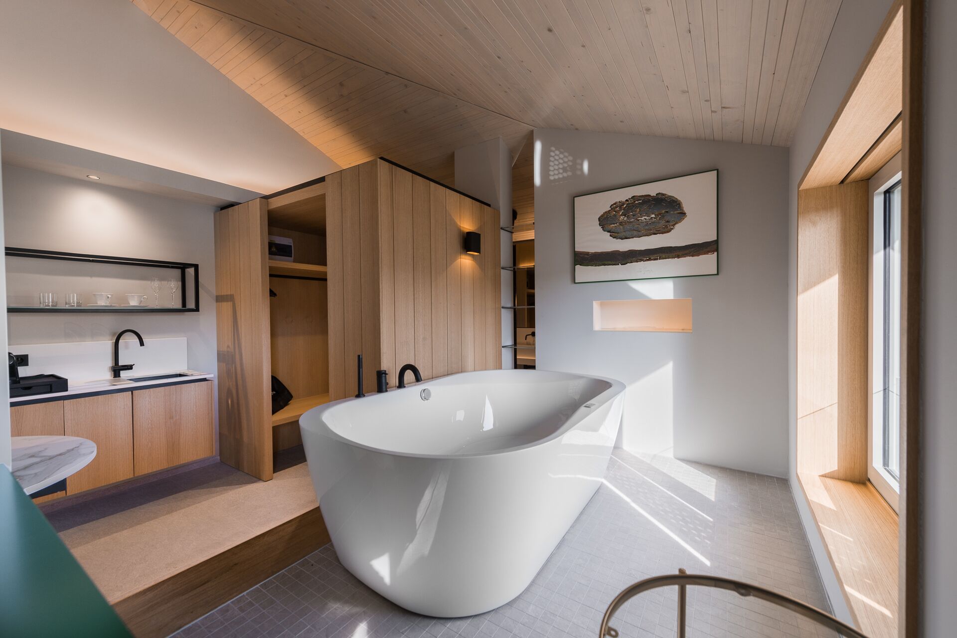 Un baño moderno con una bañera independiente, muebles de madera y un diseño minimalista.