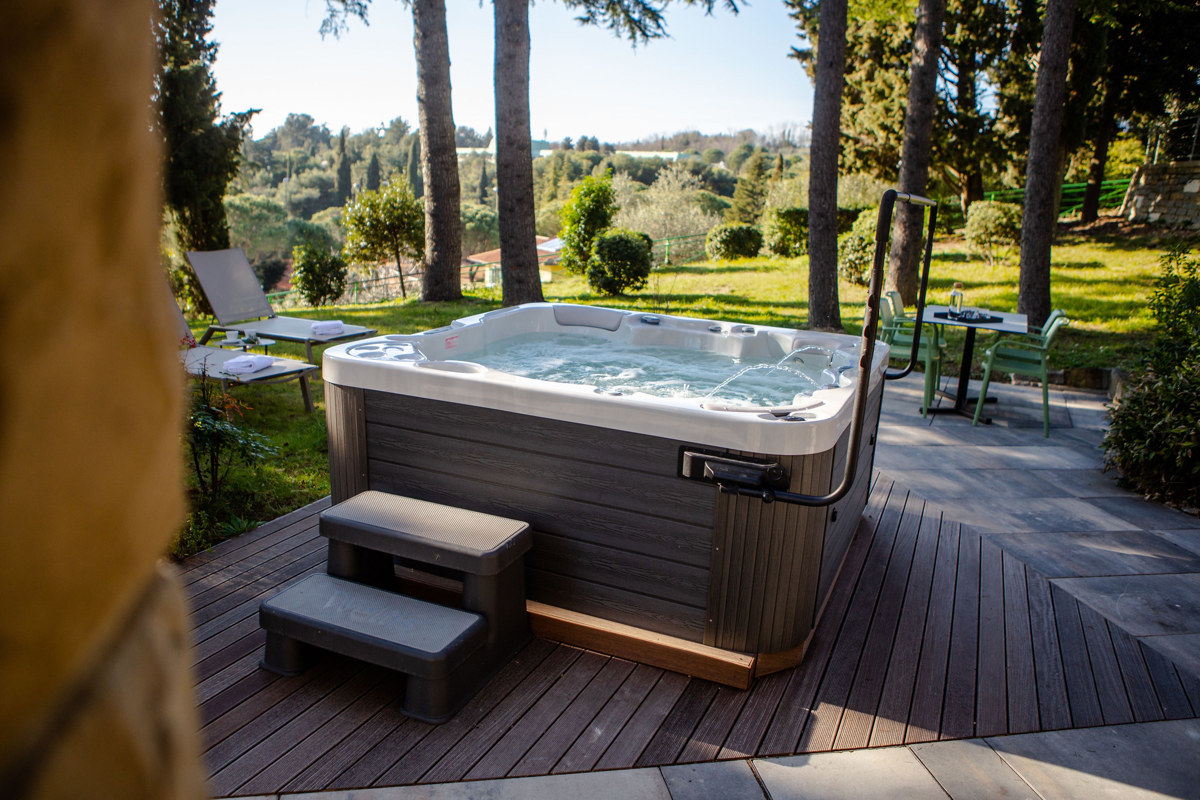 Jacuzzi sobre una terrassa de fusta amb vista a un paisatge verd.