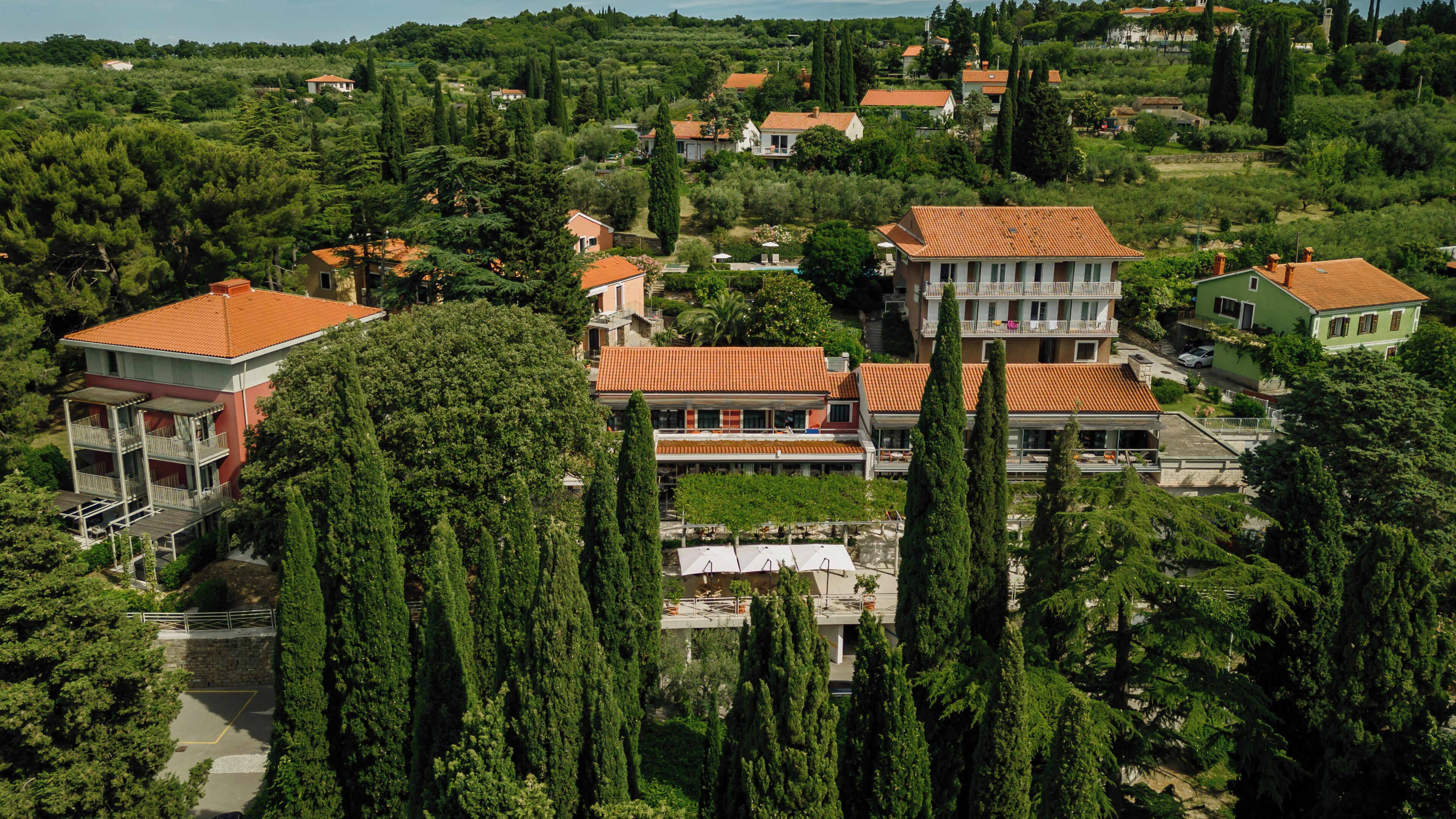 A residential area with multiple houses, some with balconies, surrounded by greenery and trees.
