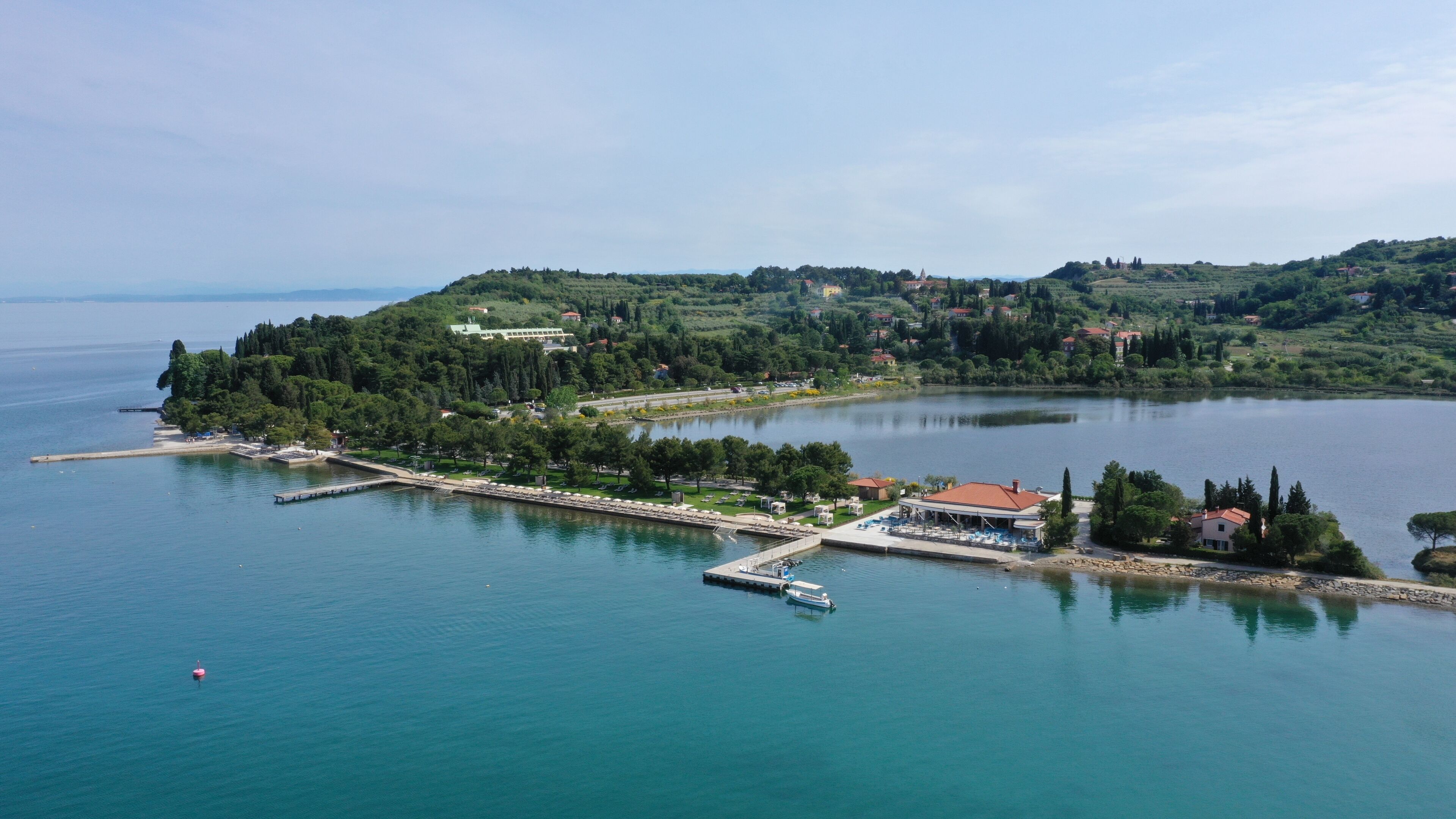 A coastal town with a marina, boats, and a small island with buildings and greenery.