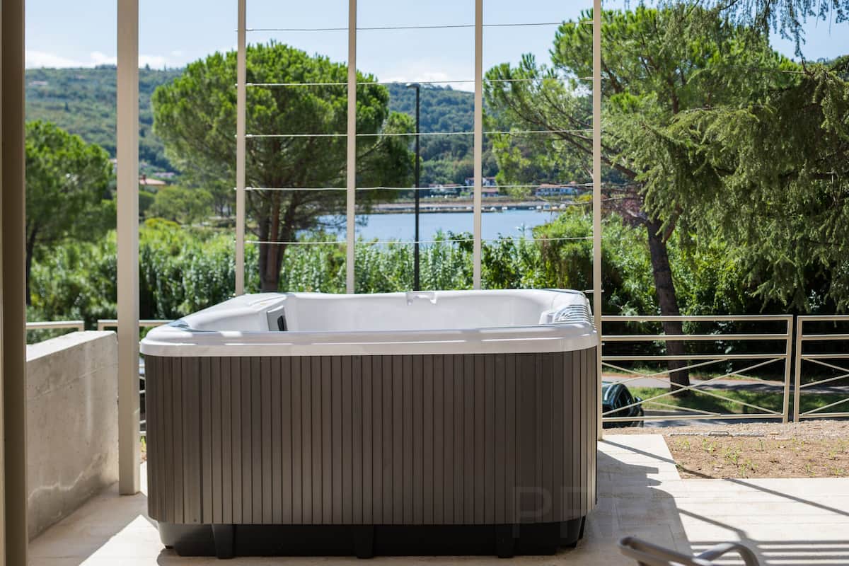 Un jacuzzi en un área exterior cubierta con vista a un lago y árboles.