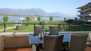A terrace with wicker furniture and a view of a lake and mountains. - Il Sogno del Lago (Manerba del Garda)