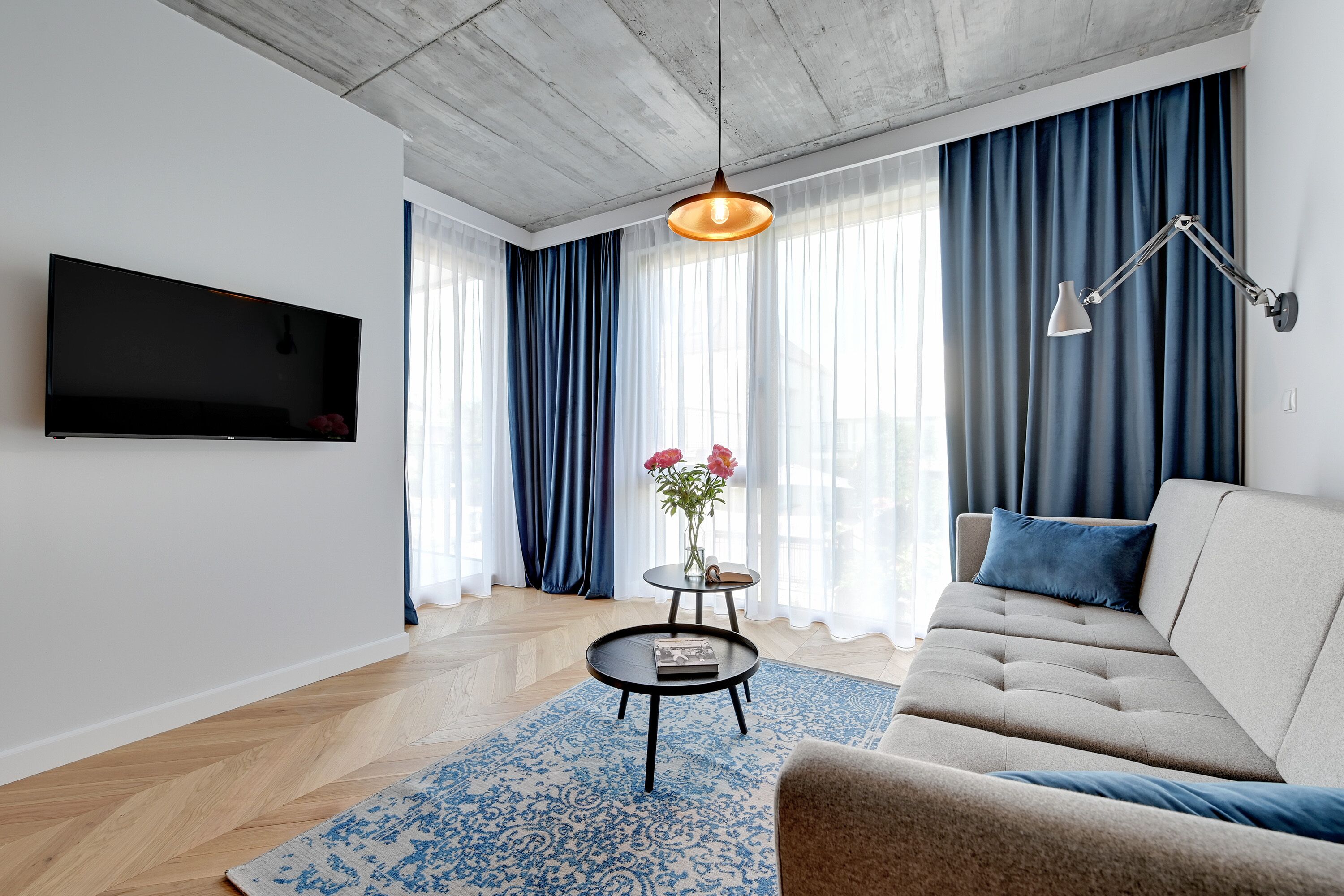 Una sala de estar moderna con un sofá, una mesa de centro, un televisor y una lámpara colgante.