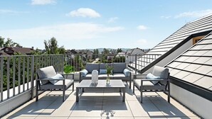 A rooftop terrace with a sofa set, a coffee table, and a potted plant. - Equus Apartments (Sopot)