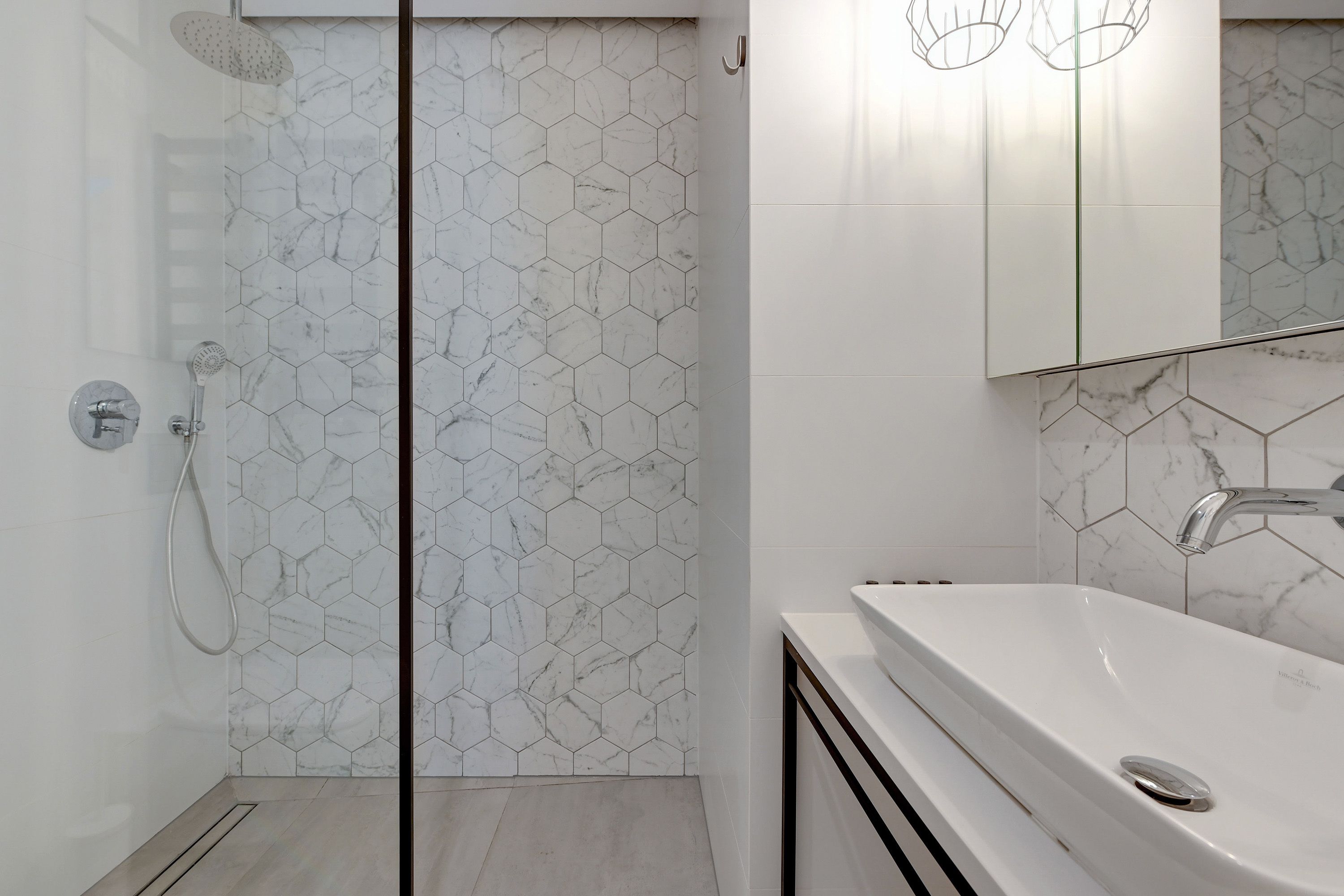 A modern bathroom with a shower, a sink, and a mirror.