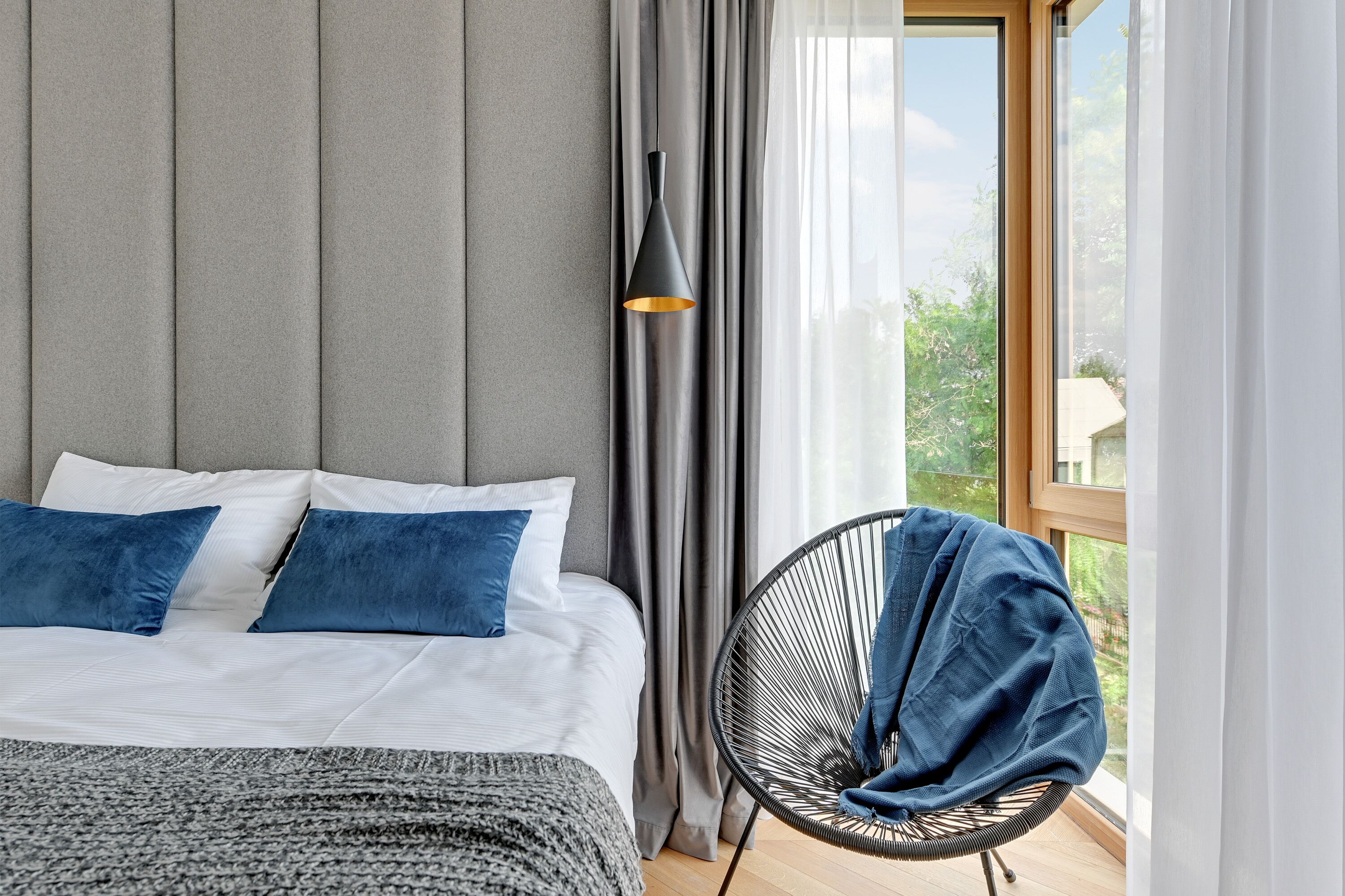 A bedroom with a bed, a chair, and a window with curtains.