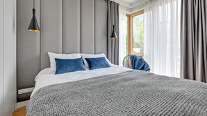 A modern hotel room with a large bed, grey curtains, and two pendant lights. - Equus Apartments (Sopot)
