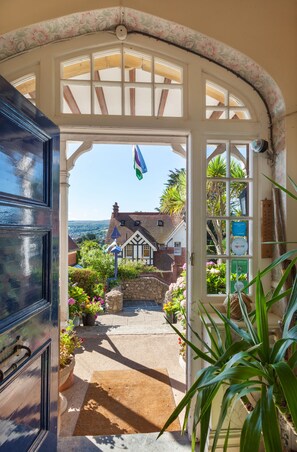 A doorway leading to a garden with a view of a traditional house and a flag. - Marston Lodge Hotel (Minehead)