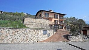 A multi-story building with a stone facade, a paved entrance, and a balcony. - Infinity (Tignale)