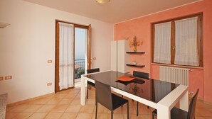 A dining area with a table and chairs, a radiator, and a window with curtains. - Infinity (Tignale)