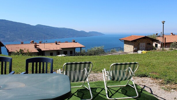 A terrace with outdoor seating, overlooking a lake and distant mountains. - Infinity (Tignale)