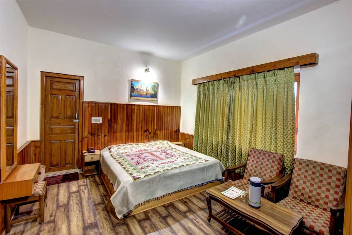 A room with a bed, a wooden wardrobe, a desk, a chair, and a window with curtains.