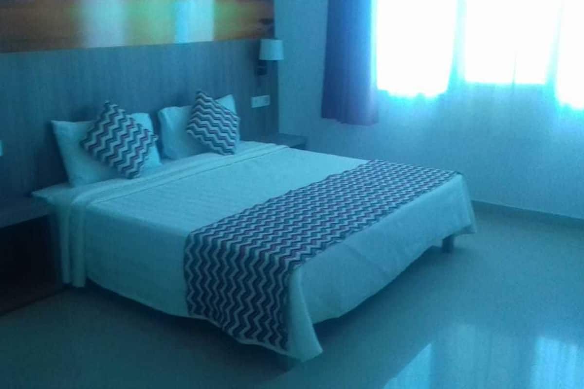 Ein Hotelzimmer mit Bett, Nachttischen und einem Vorhangfenster.
