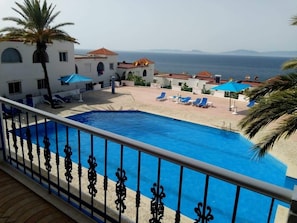 Zona de piscina con vista despejada al mar y montañas al fondo.