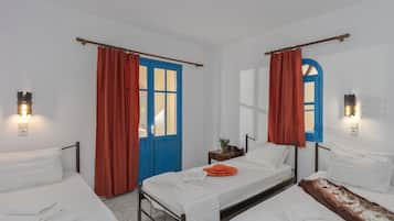 A room with two beds, a blue door, and red curtains.