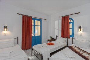 A room with two beds, a blue door, and red curtains. - Palm Bay (Agios Nikolaos)