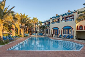A swimming pool with lounge chairs and palm trees. - Palm Bay (Agios Nikolaos)