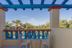 A balcony with blue railings, white chairs, and palm trees in the background. - Palm Bay (Agios Nikolaos)