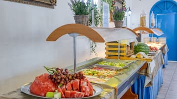 A buffet with various food items, including watermelon and grapes, and a blue door in the background.