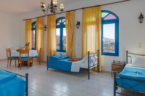 A hotel room with a bed, a table with chairs, and a view through the window. - Palm Bay (Agios Nikolaos)