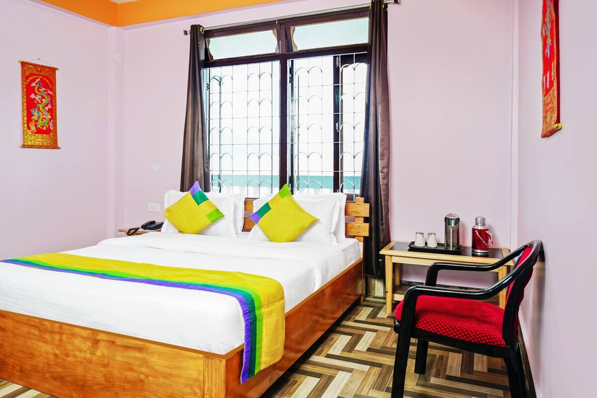 A hotel room with a bed, a desk, a chair, a window, and a wall decoration.